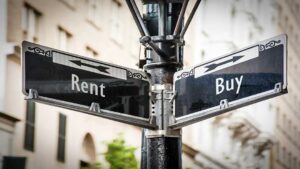 A home inspector examines a heating system while a homeowner listens and observes in a basement utility room.